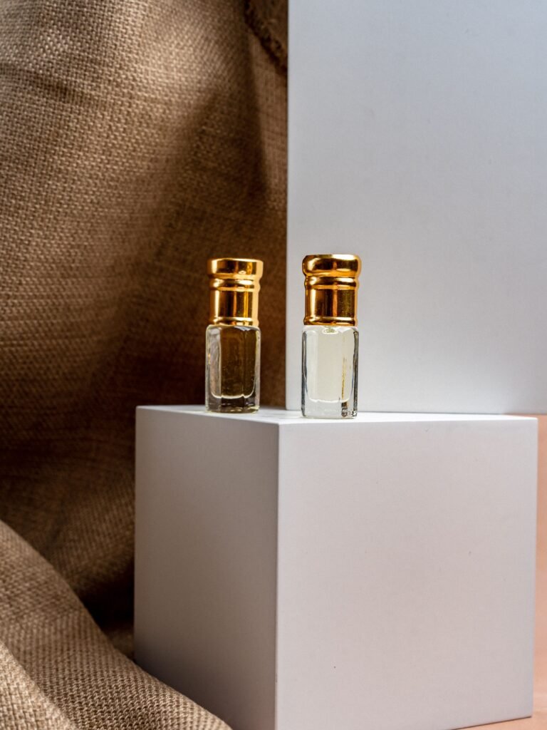 Close-up of two elegant perfume bottles with gold caps on a minimalist white display, evoking luxury.